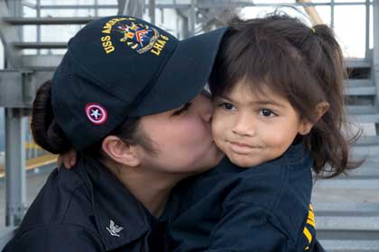 Navy Petty OFficer 3rd Class Elizabeth Robles kisses her daughter on the pier at naval Base San Diego as the amphibious assault ship USS America returned from its maiden deployment, Feb. 2, 2018. U.S. Navy photo by PO2 Jonathan A. Colon