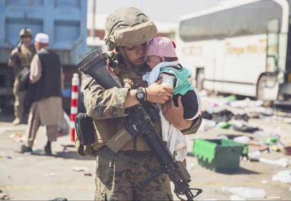 A Marine holds a baby while a family in-processes at Hamid Karzai International Airport, Kabul, Afghanistan, Aug. 28, 2021. U.S. service members are assisting the Department of State with a non-combatant evacuation operation in Afghanistan. 